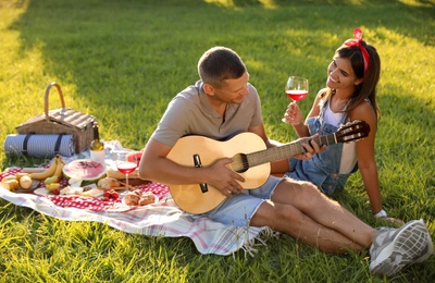Photo of Happy couple with guitar on picnic in park