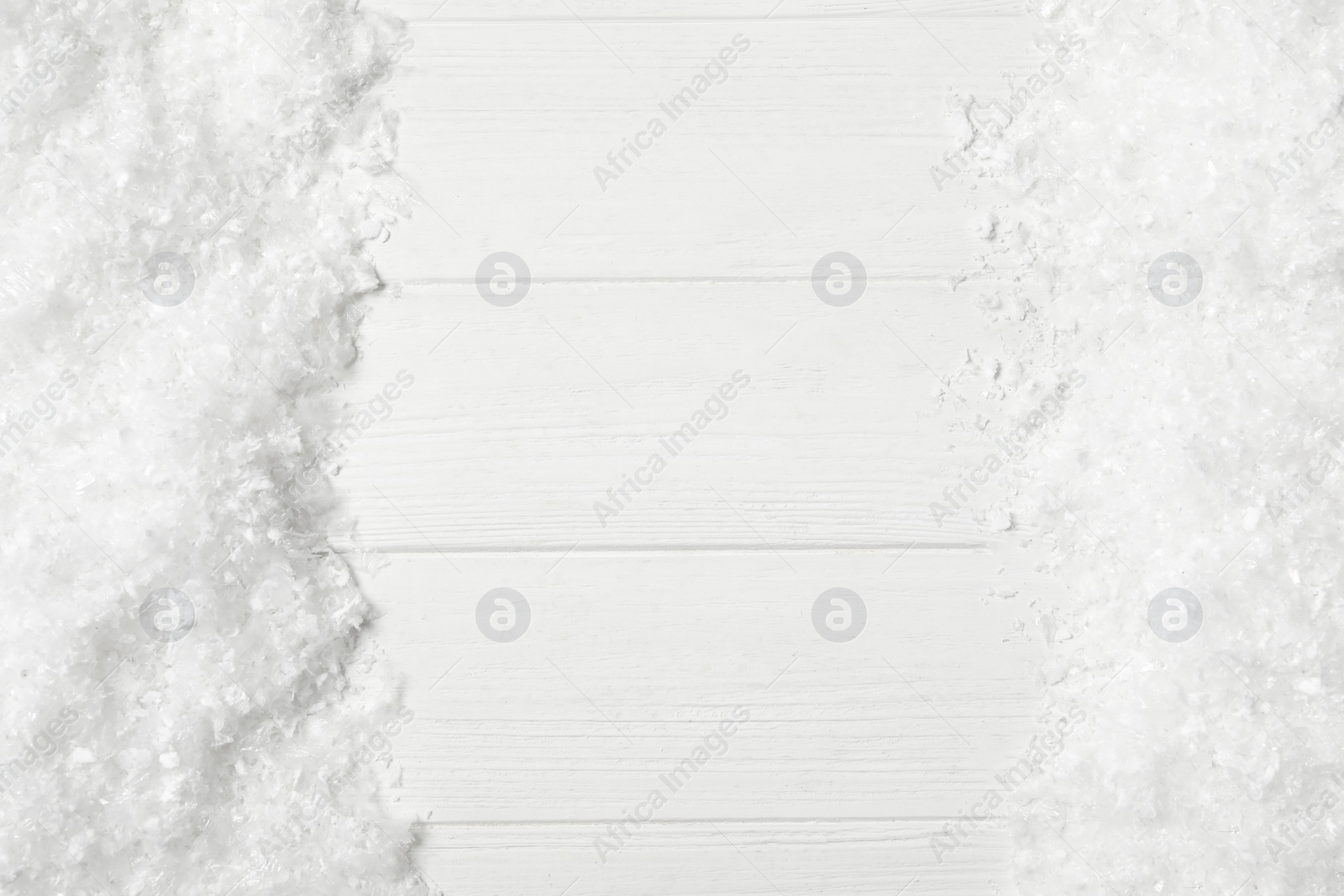 Photo of Frame made of snow on white wooden background, top view with space for text. Christmas season