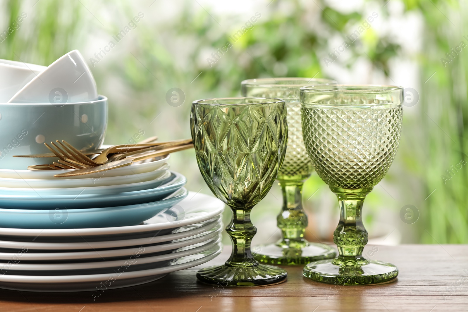 Photo of Beautiful ceramic dishware, glasses and cutlery on wooden table outdoors