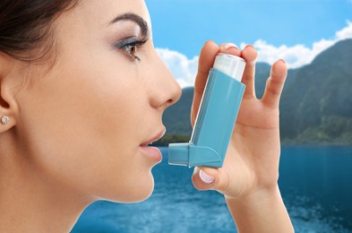 Woman using asthma inhaler near lake. Emergency first aid during outdoor recreation