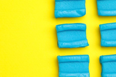 Photo of Blue bubble gums on yellow background, flat lay. Space for text