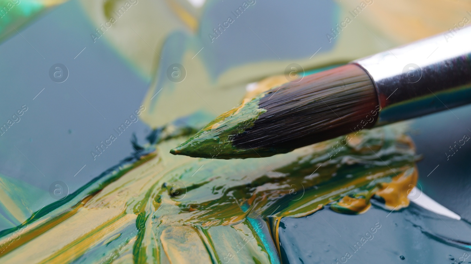 Photo of Brush on artist's palette with mixed paints, closeup