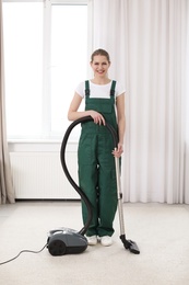 Photo of Female worker cleaning carpet with vacuum in living room