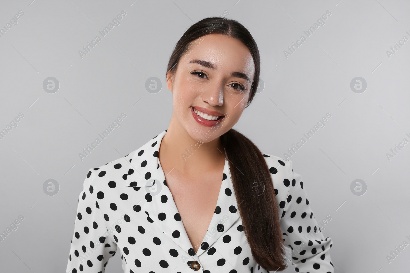 Photo of Portrait of beautiful young woman in polka dot blouse on light grey background