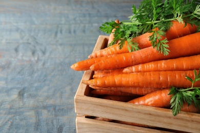 Photo of Crate of fresh carrots on wooden background, closeup. Space for text