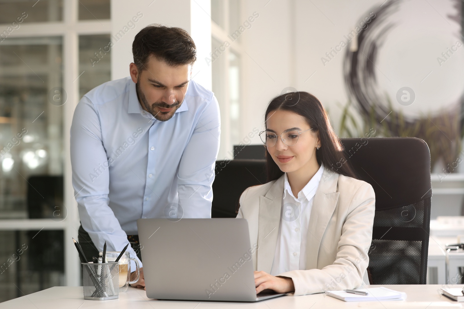 Photo of Colleagues working on laptop at desk in office