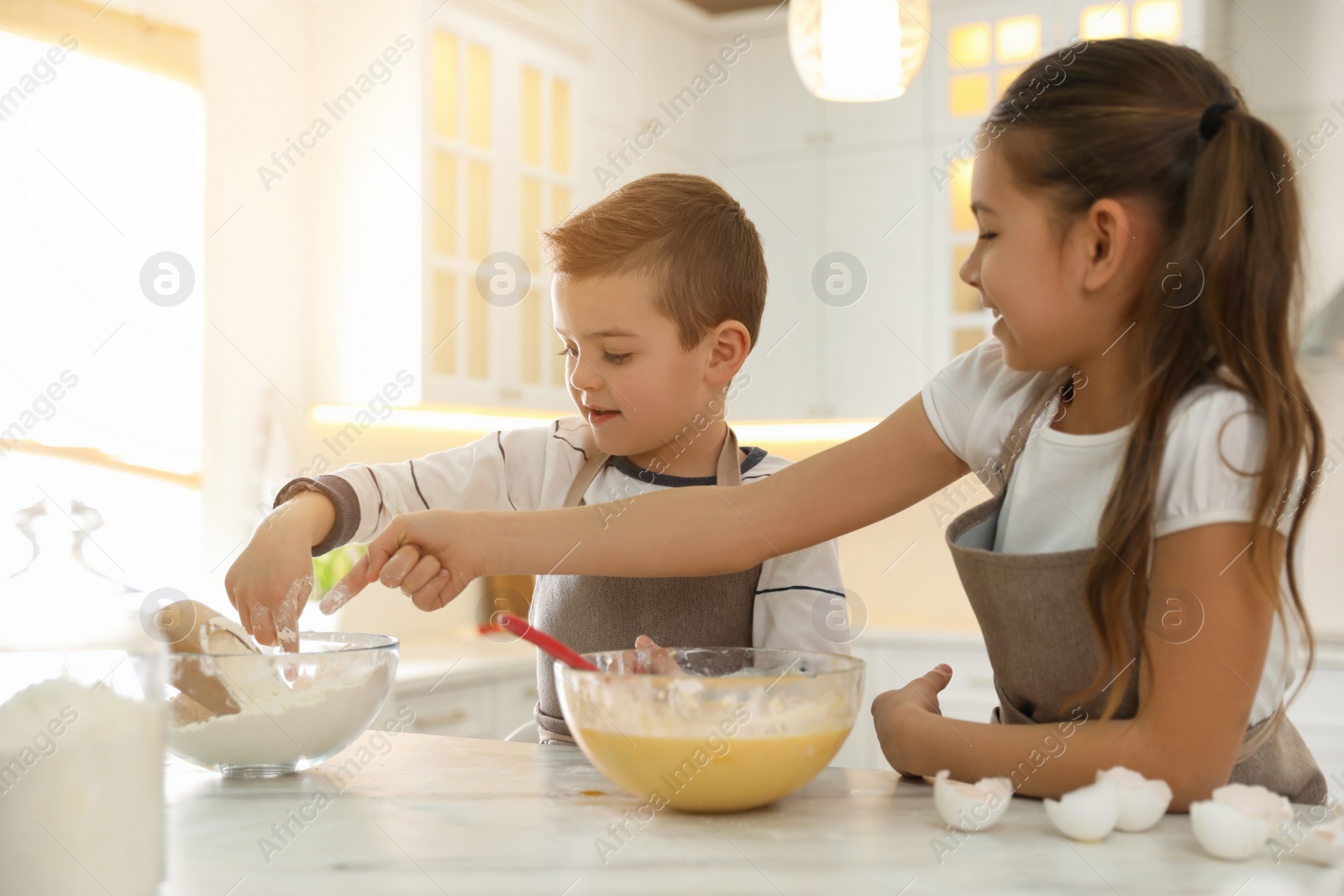 Photo of Cute little children cooking dough together in kitchen