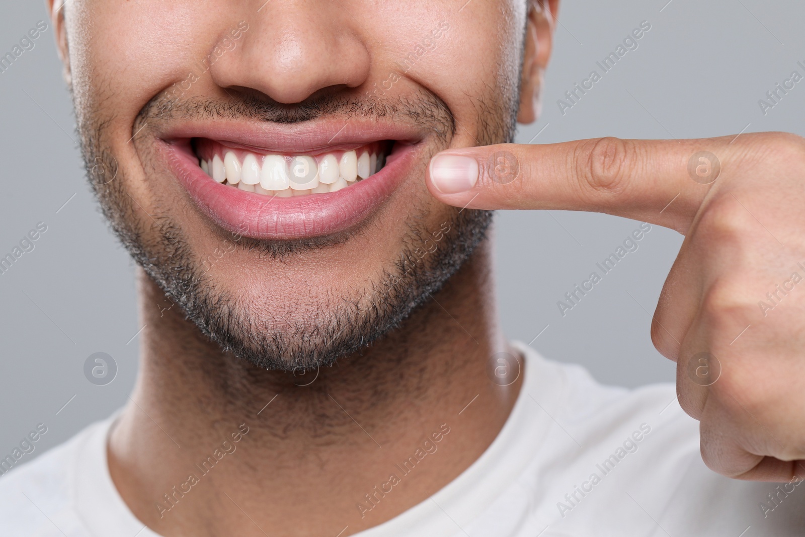 Photo of Man showing healthy gums on grey background, closeup