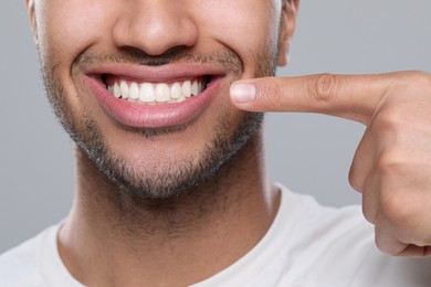 Man showing healthy gums on grey background, closeup