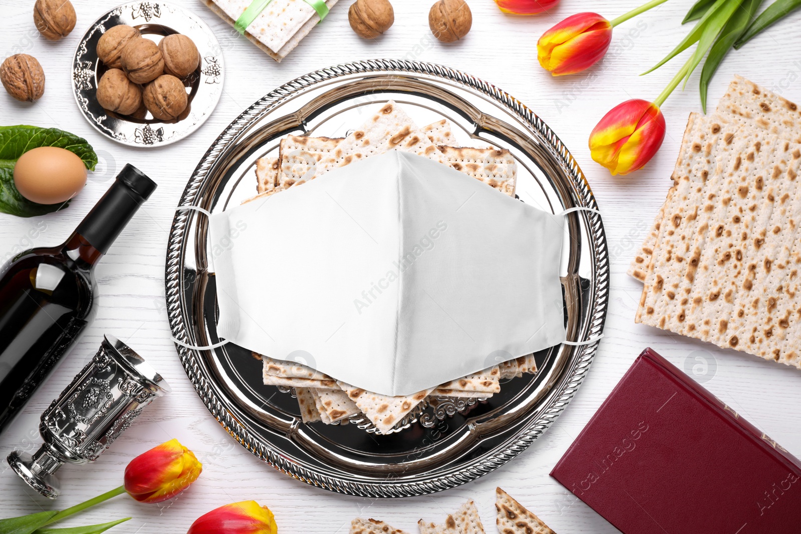 Image of Coronavirus pandemic. Flat lay composition with symbolic Pesach (Passover Seder) items and protective face mask on white wooden table