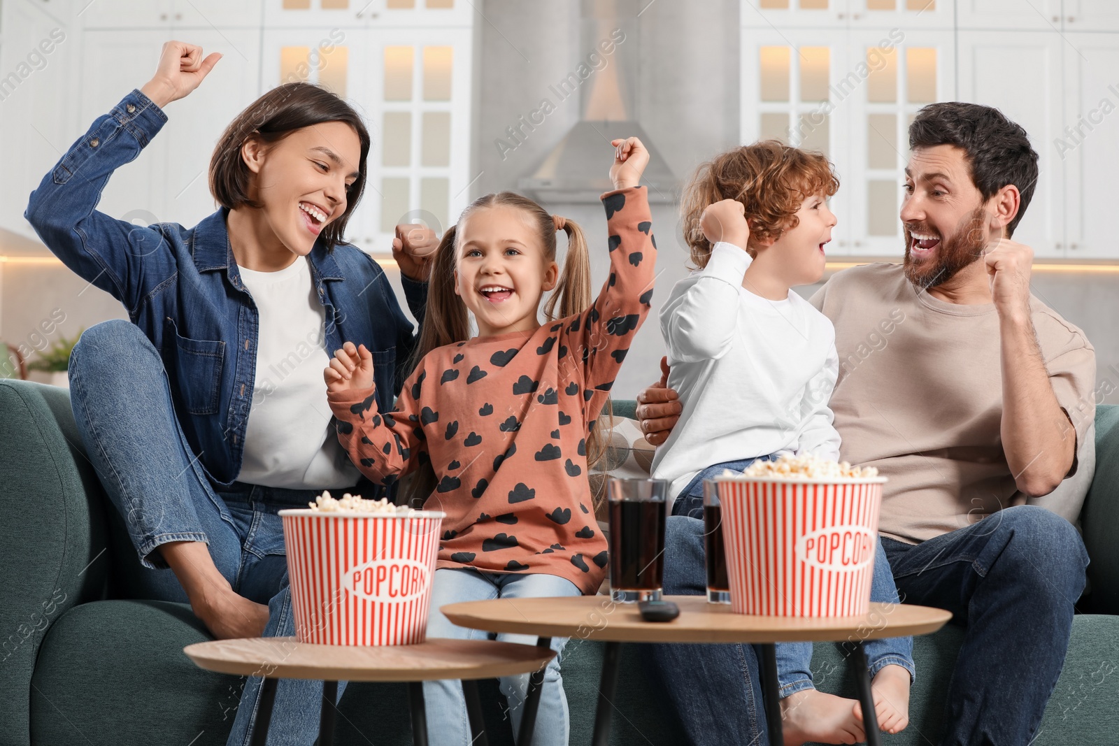 Photo of Happy family watching TV with popcorn on sofa at home