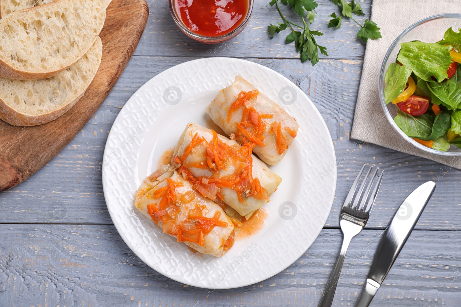 Photo of Delicious cabbage rolls served on grey wooden table, flat lay