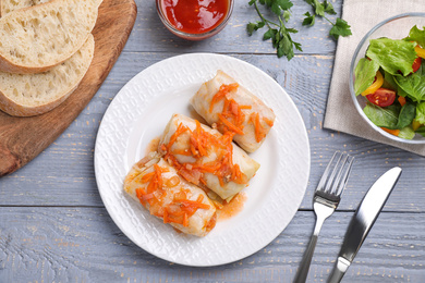 Photo of Delicious cabbage rolls served on grey wooden table, flat lay