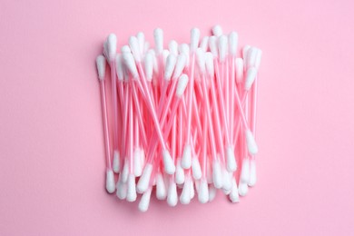Photo of Heap of cotton buds on pink background, top view