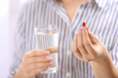 Photo of Young woman with pill and glass of water, closeup