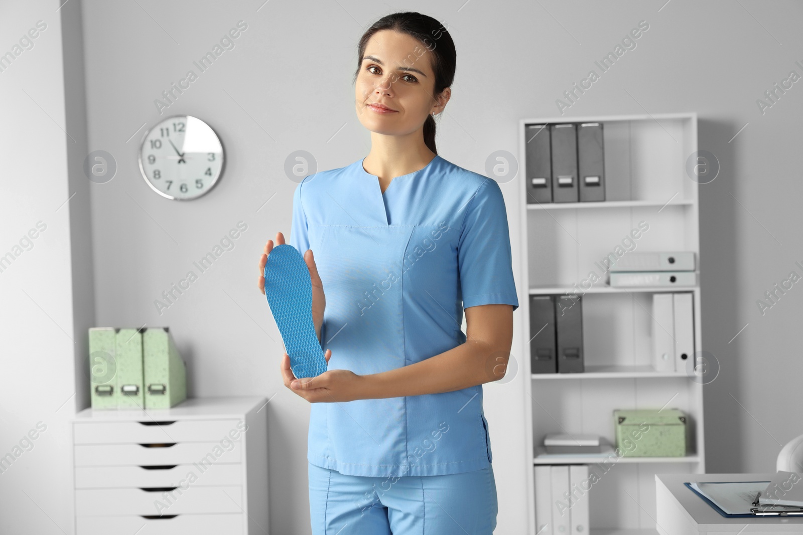 Photo of Beautiful female orthopedist showing insole in hospital