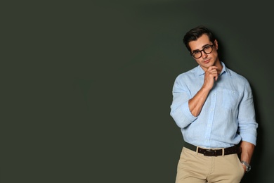 Handsome young man in stylish clothes with glasses on dark background. Space for text