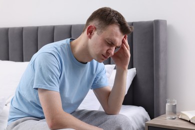 Photo of Sad man suffering from headache on bed indoors, space for text