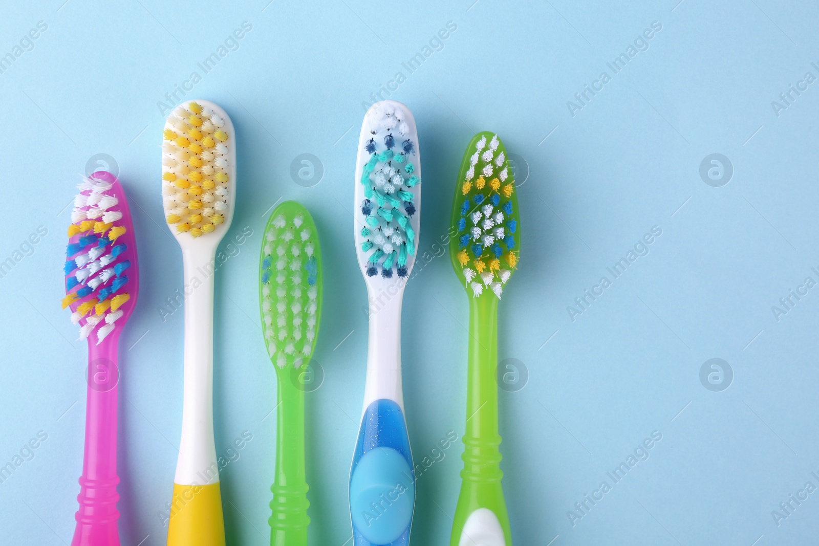 Photo of Many different toothbrushes on light blue background, flat lay. Space for text