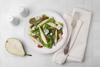 Photo of Delicious pear salad served on white tiled table, flat lay