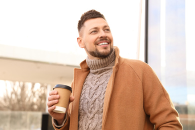 Photo of Man with cup of coffee on city street in morning