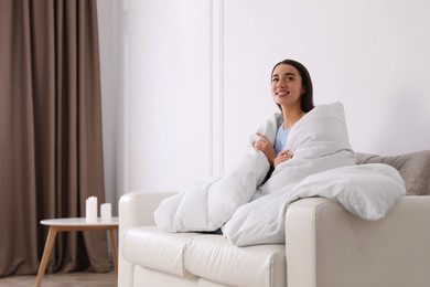 Woman covered in blanket resting on sofa, space for text
