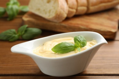 Photo of Tasty sauce with basil leaves in gravy boat on wooden table, closeup