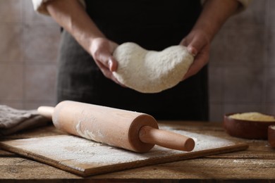 Photo of Man making dough at wooden table, closeup