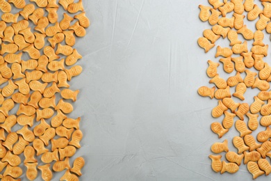 Photo of Delicious goldfish crackers on grey table, flat lay. Space for text