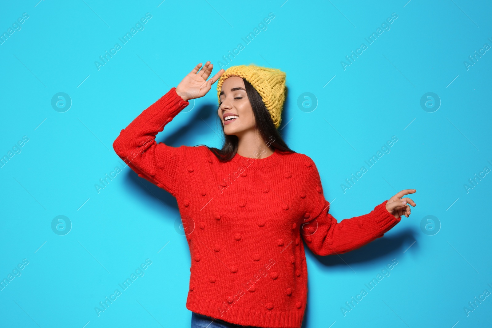 Photo of Young woman in warm sweater and hat on color background. Celebrating Christmas