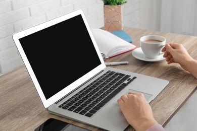 Woman using laptop at table, closeup. Space for design