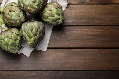 Photo of Fresh raw artichokes on wooden table, flat lay. Space for text