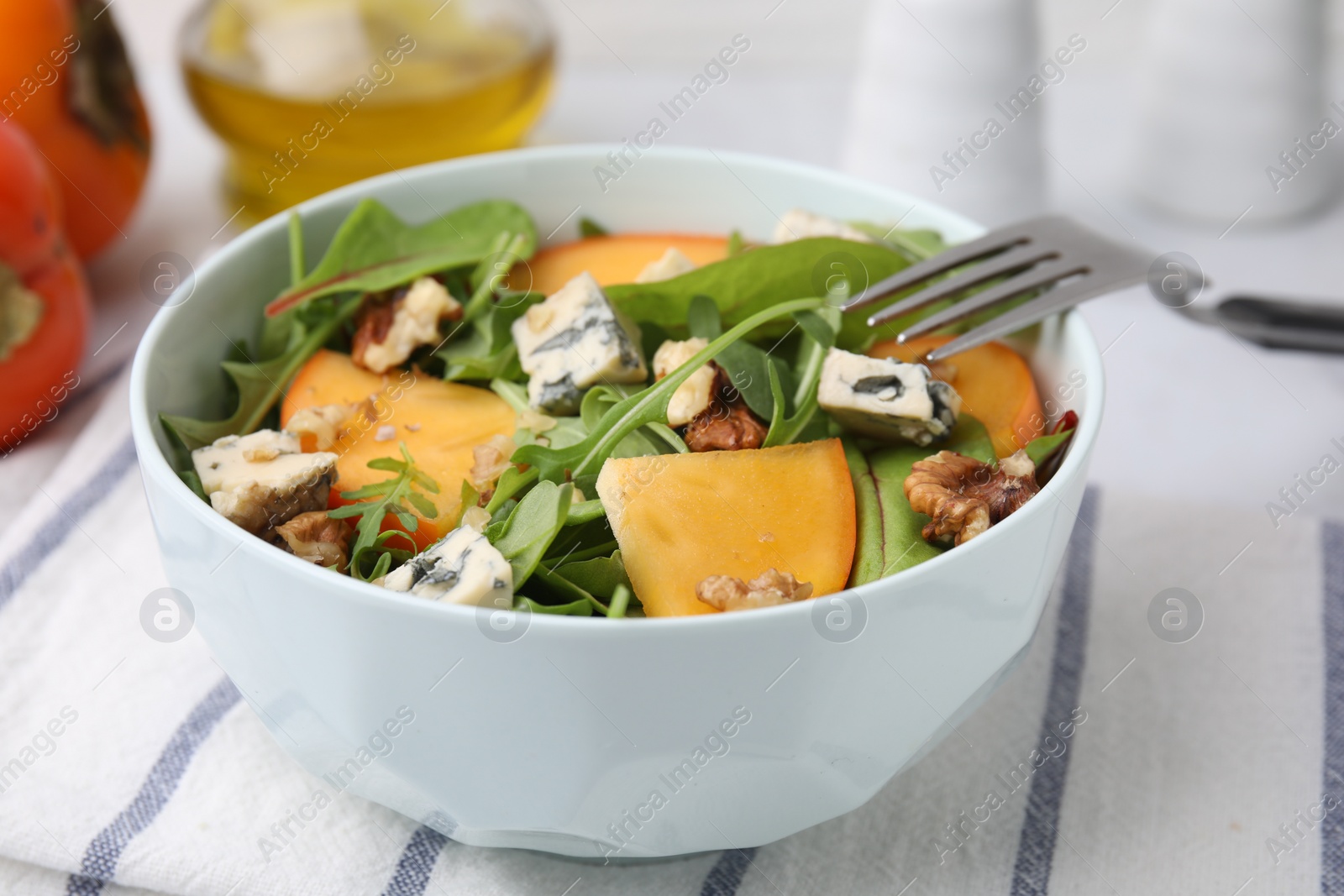 Photo of Tasty salad with persimmon, blue cheese and walnuts served on table, closeup