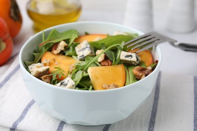 Tasty salad with persimmon, blue cheese and walnuts served on table, closeup