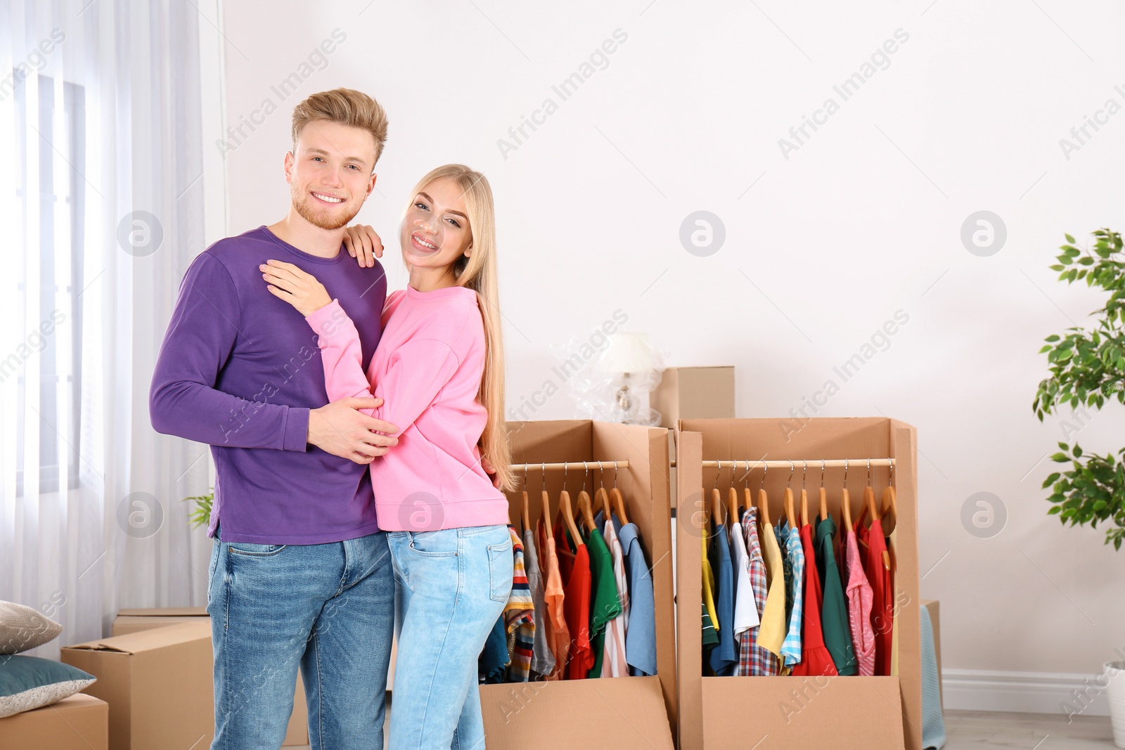 Photo of Young couple near wardrobe boxes at home. Space for text