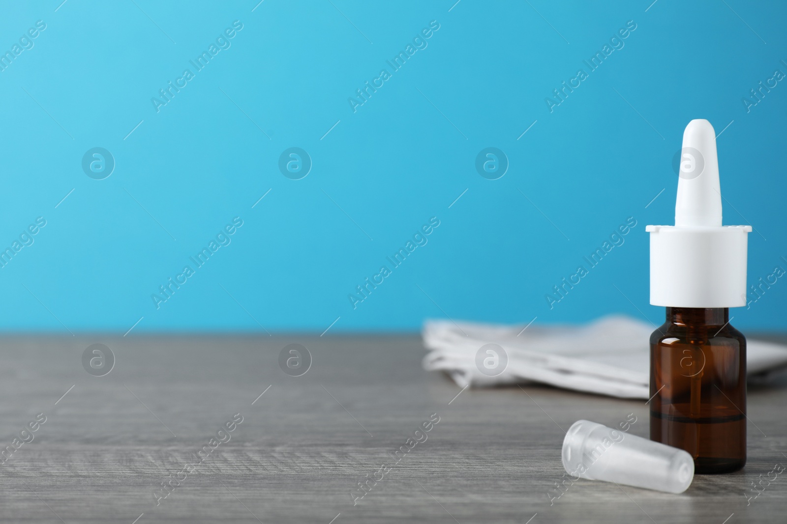 Photo of Bottle of nasal spray on grey wooden table. Space for text