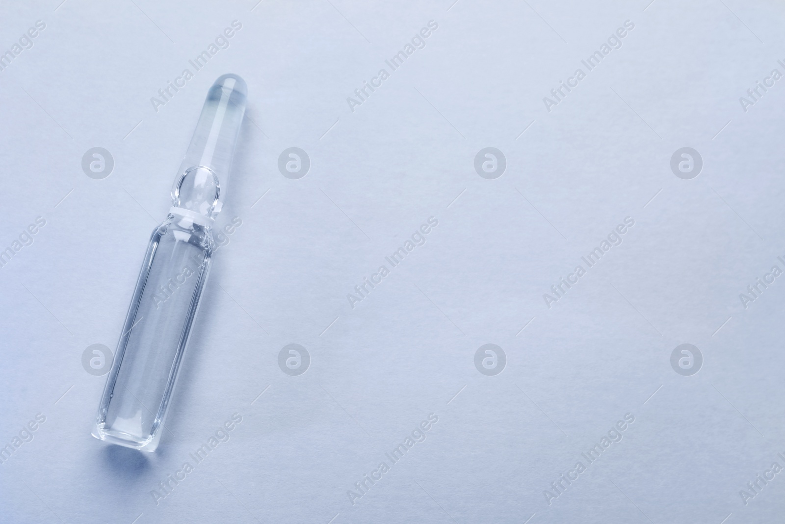 Photo of Pharmaceutical ampoule with medication on white background, top view. Space for text