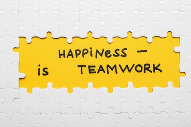 Recruitment concept. Phrase Happiness Is Teamwork surrounded by assembled white jigsaw puzzle pieces, top view