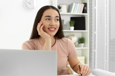 Photo of Home workplace. Happy woman working on laptop in room