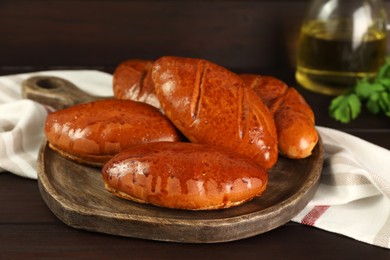 Delicious baked pirozhki on wooden table, closeup