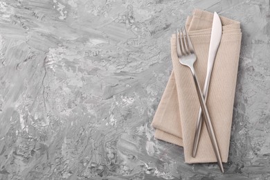 Photo of Elegant silver cutlery and kitchen towel on grey textured table, top view. Space for text