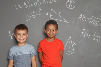 Little school children and mathematical formulas on grey background