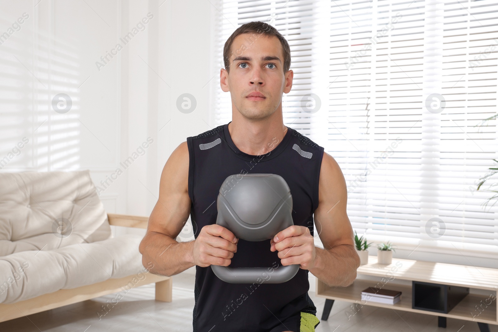 Photo of Handsome man training with kettlebell at home