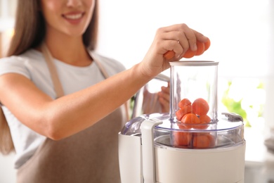 Photo of Young woman making tasty fresh juice in kitchen, closeup