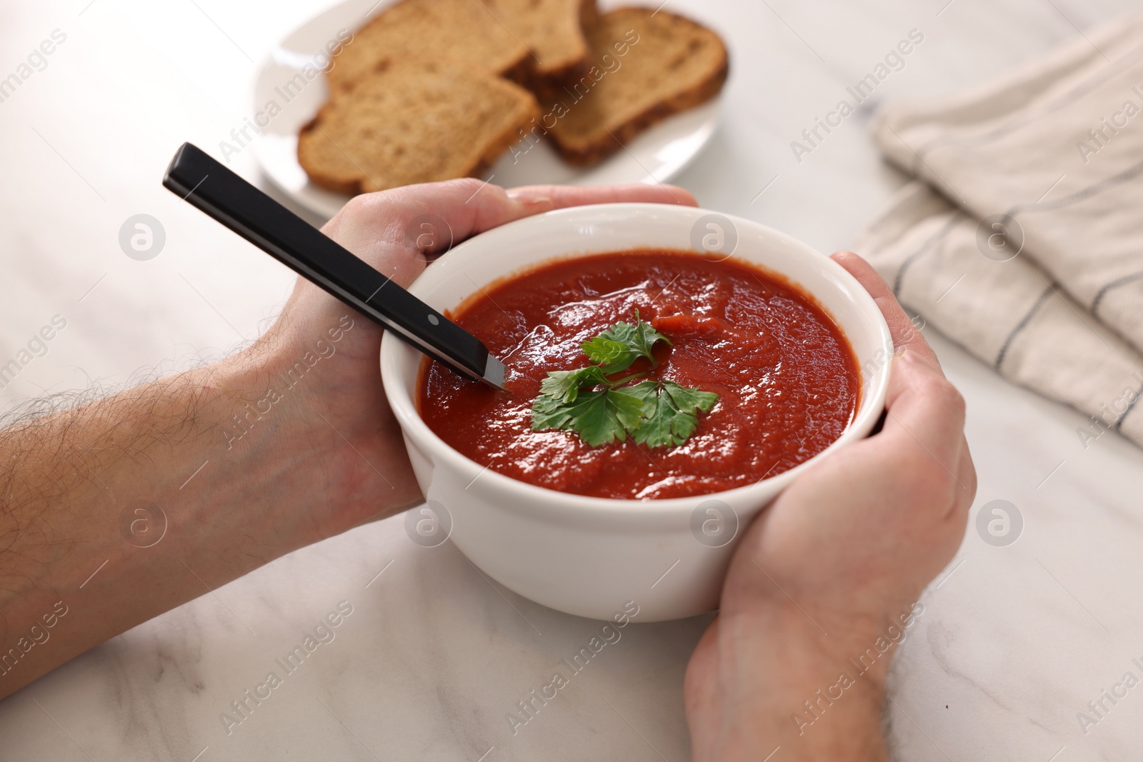 Photo of Man with delicious tomato soup at light marble table, closeup