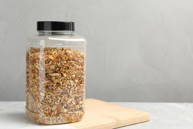 Photo of Jar with dried orange zest seasoning on light grey table. Space for text