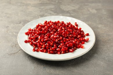 Photo of Tasty ripe pomegranate grains on grey table