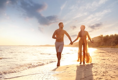 Photo of Happy young couple running together on beach at sunset