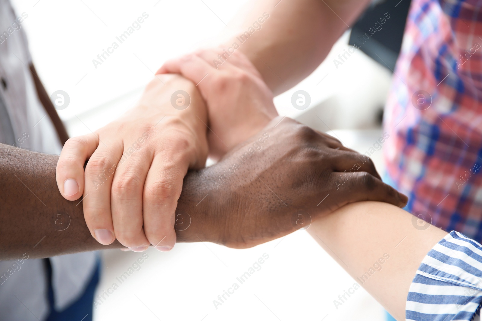 Photo of People holding hands on light background, closeup. Unity concept