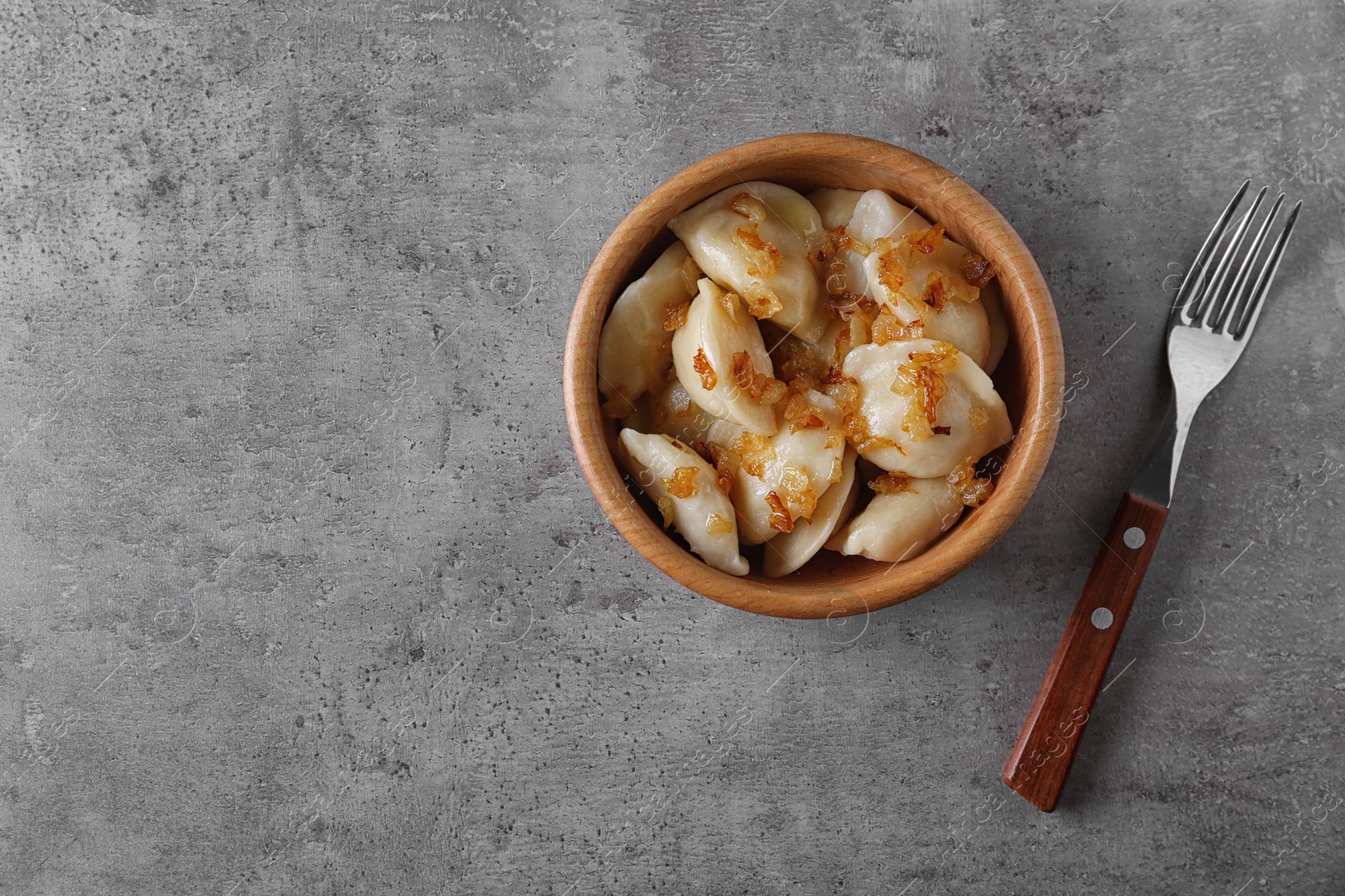 Photo of Delicious cooked dumplings with fried onion on grey table, flat lay. Space for text